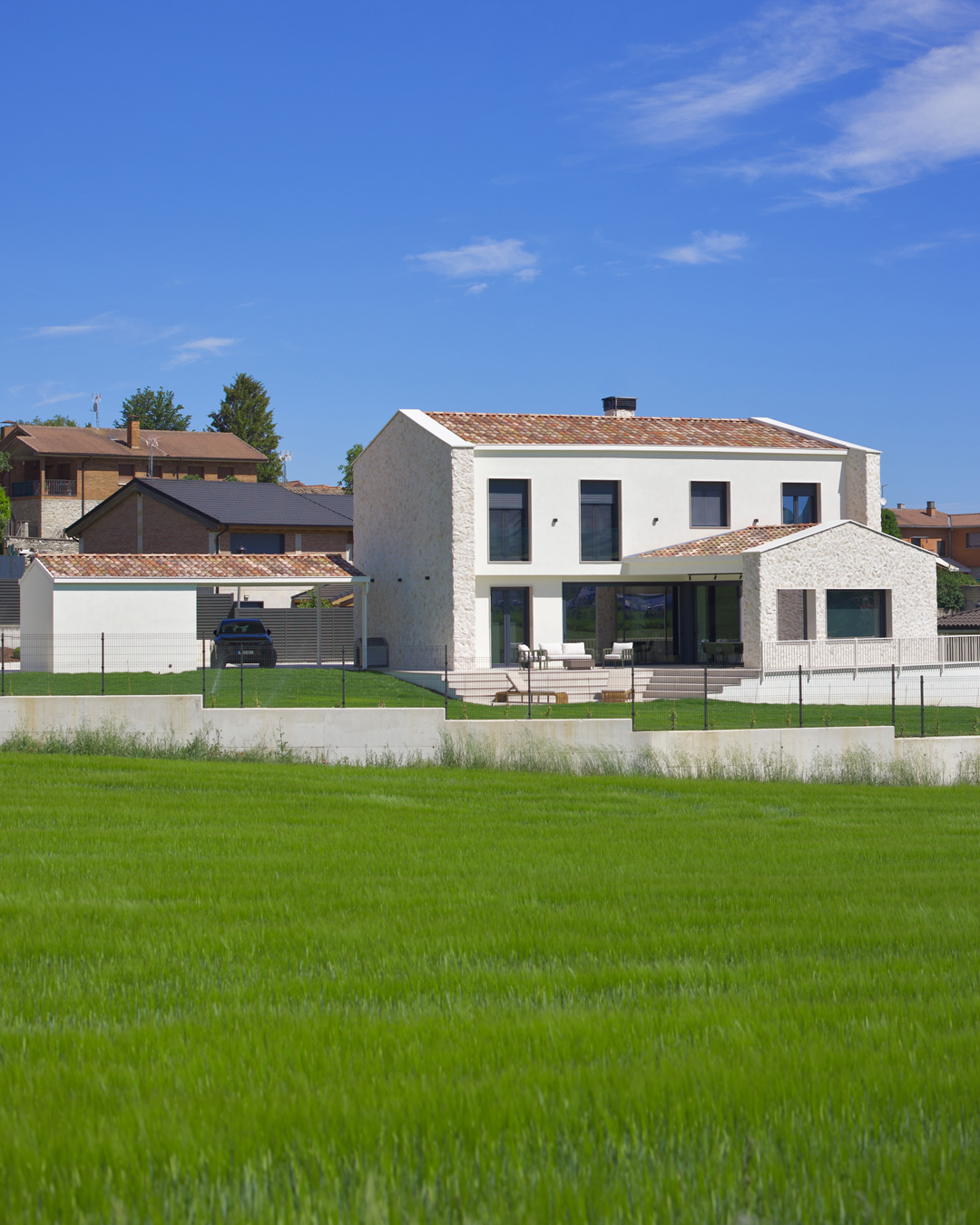 Arquitectura exterior de Casa V por a.bolado arquitectura: fachada de piedra natural, volumetría moderna y diseño integrado en el paisaje