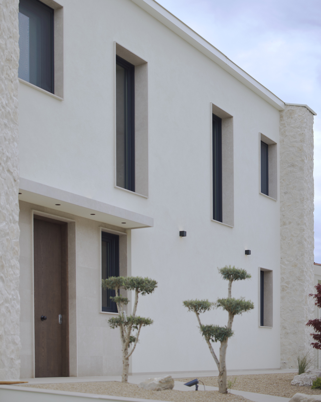 Arquitectura exterior de Casa V por a.bolado arquitectura: fachada de piedra natural, volumetría moderna y diseño integrado en el paisaje