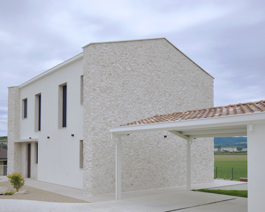 Arquitectura exterior de Casa V por a.bolado arquitectura: fachada de piedra natural, volumetría moderna y diseño integrado en el paisaje