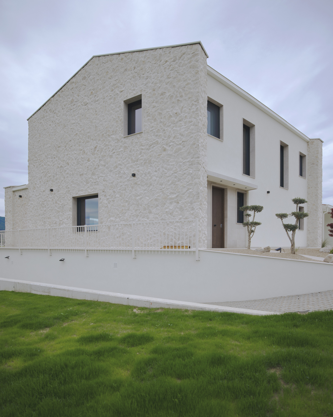 Arquitectura exterior de Casa V por a.bolado arquitectura: fachada de piedra natural, volumetría moderna y diseño integrado en el paisaje