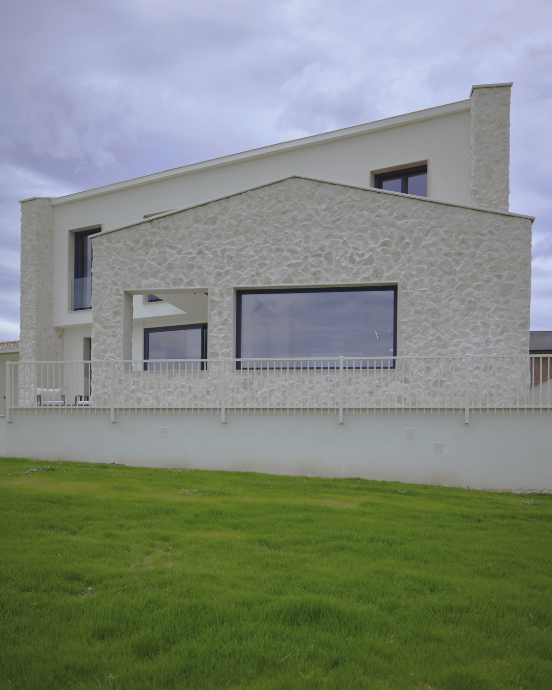 Arquitectura exterior de Casa V por a.bolado arquitectura: fachada de piedra natural, volumetría moderna y diseño integrado en el paisaje