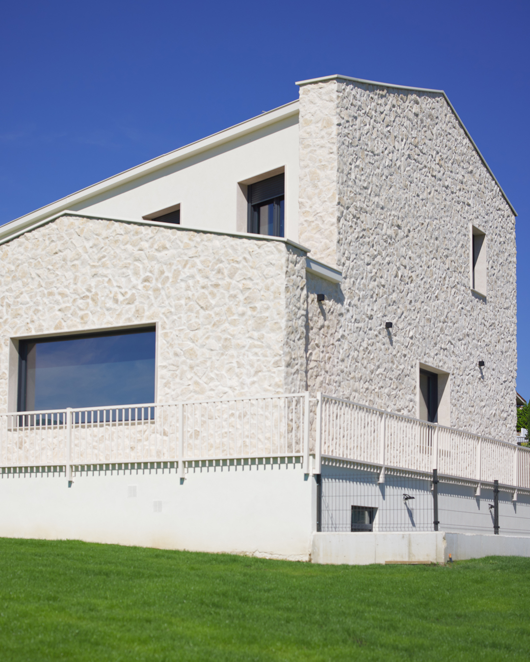 Arquitectura exterior de Casa V por a.bolado arquitectura: fachada de piedra natural, volumetría moderna y diseño integrado en el paisaje